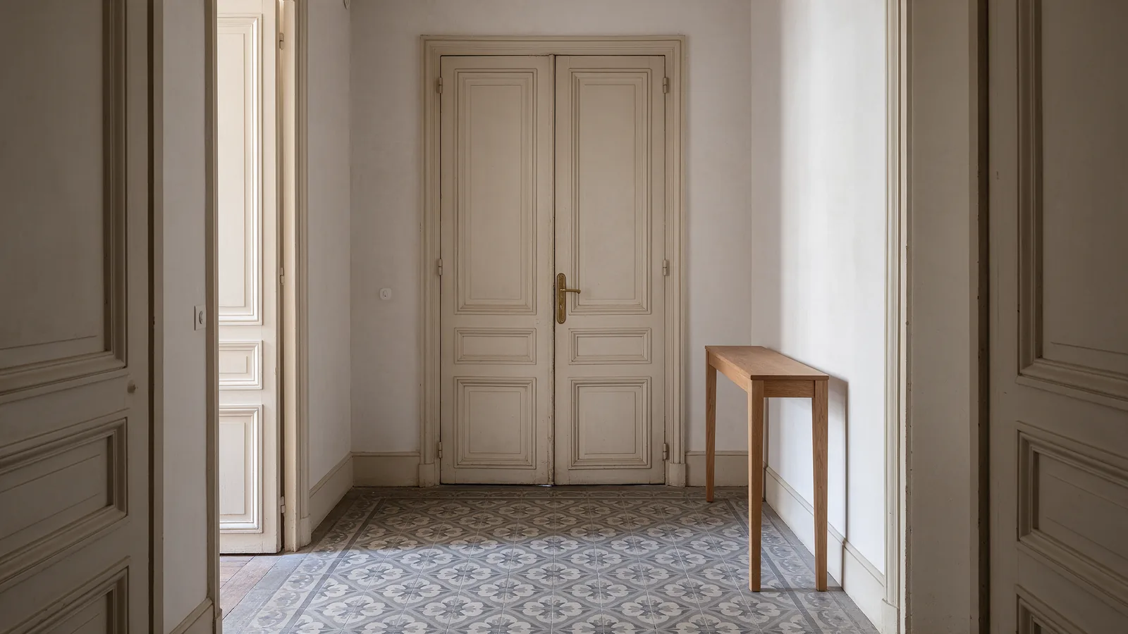 Entrée d'appartement ancien, portes à double battant et sol en carreaux de ciment